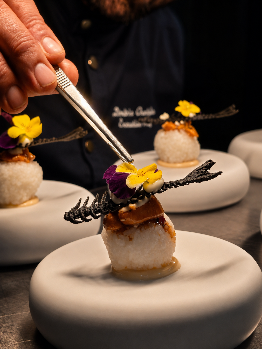 Rice ball with porcini, edible flowers and squid-ink lace