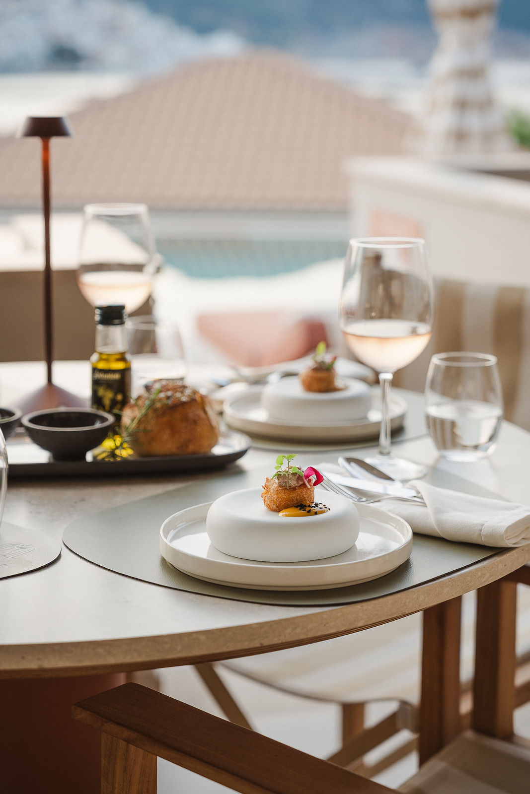 A plated course on the terrace, with rosé wine and a view of the pool